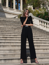 a lady wears a black boat neck sweater with black pants